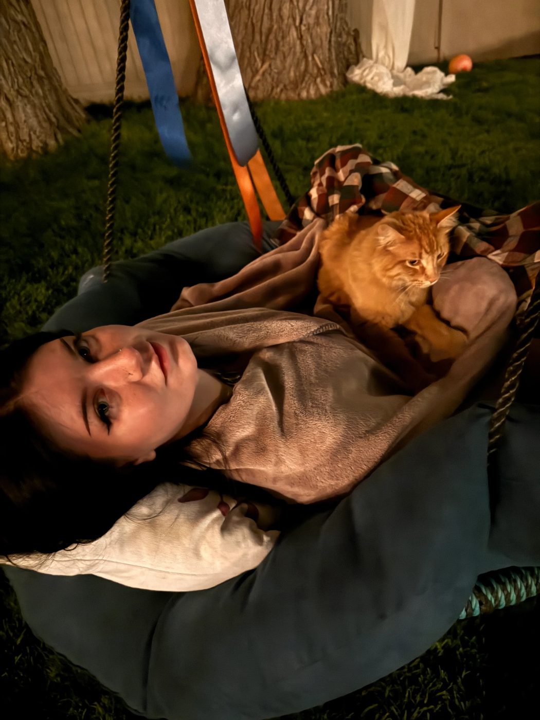 Brianna relaxing on a hammock swing with an orange cat
